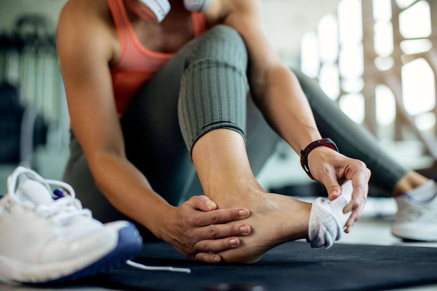 Person holding a sore ankle after exercise, illustrating leg and foot fatigue.