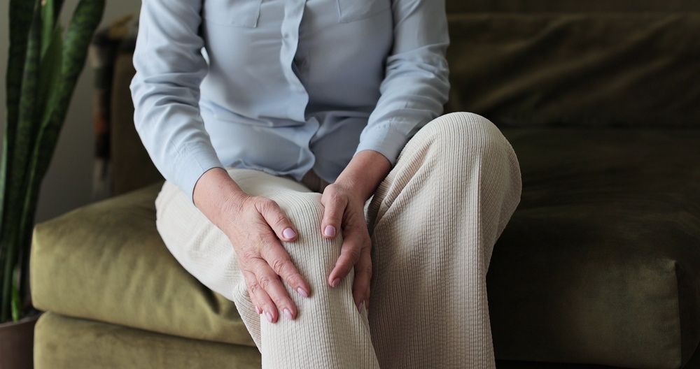 Person sitting with hands on their legs, representing heavy legs from poor circulation.