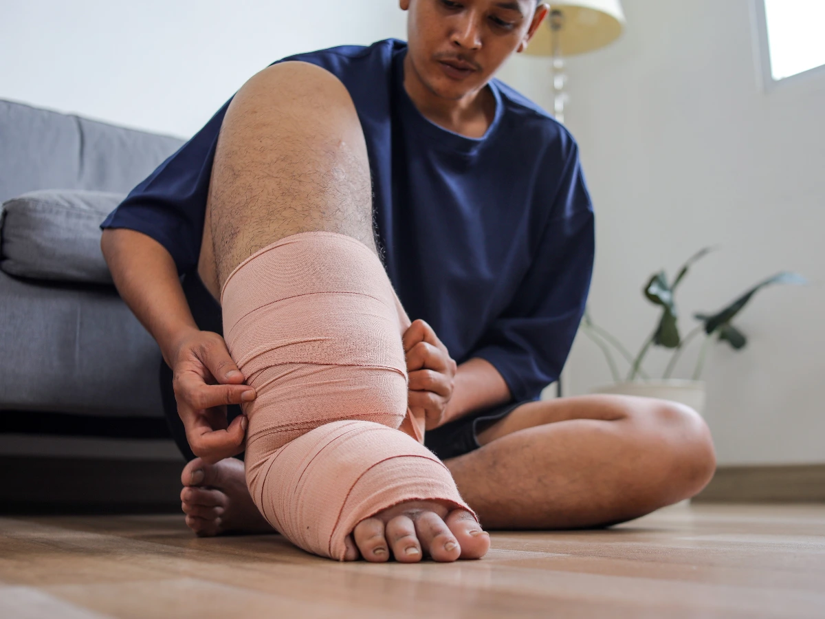 Person applying a compression bandage to their leg.